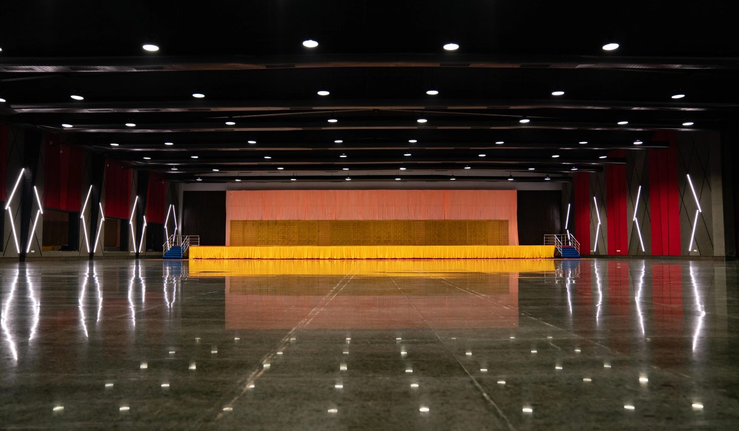 Emerald hall empty, showing the black steel ceiling, crimson wall panels with diamond lights, the gold-lit stage and the mirror-polished granite floor