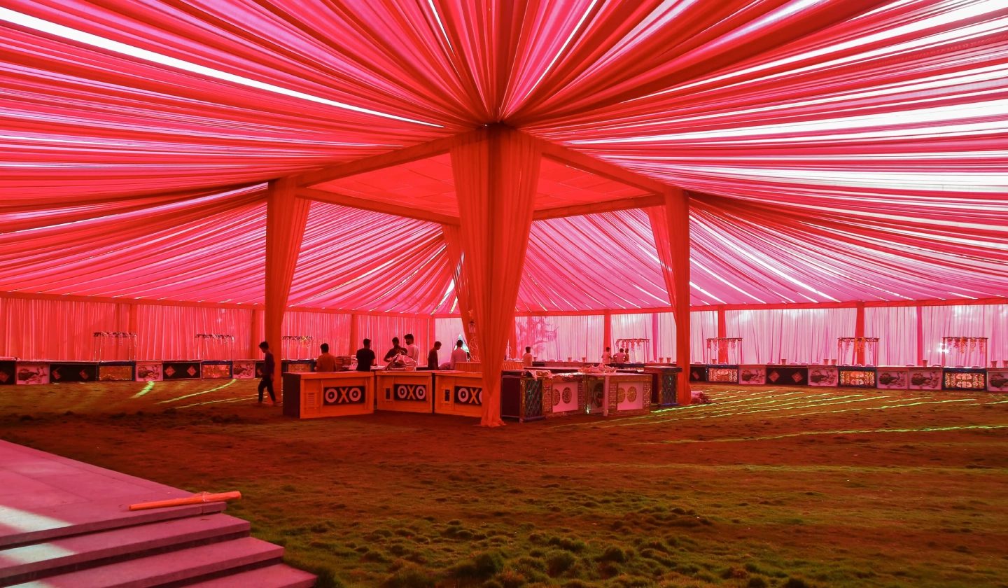 Crimson shamiana canopy with radial pleating pitched on the grounds